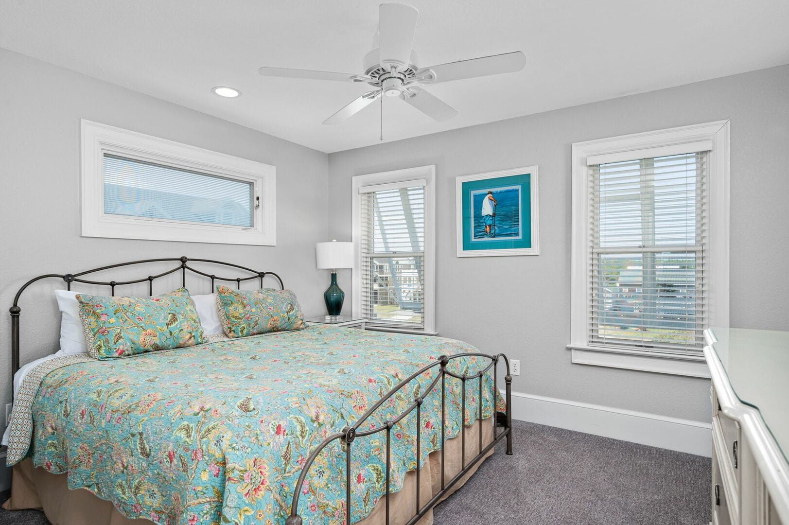 Bedroom with floral bedding, windows.