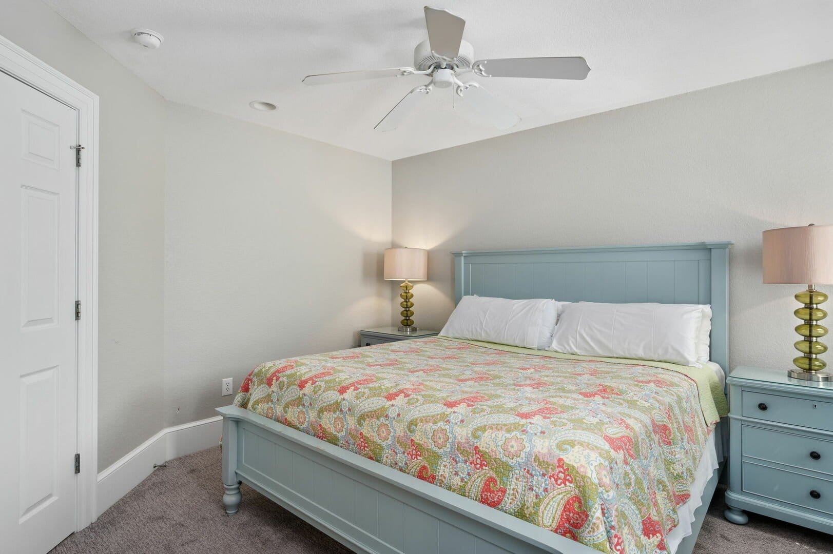 Bedroom with bed, lamps, ceiling fan.