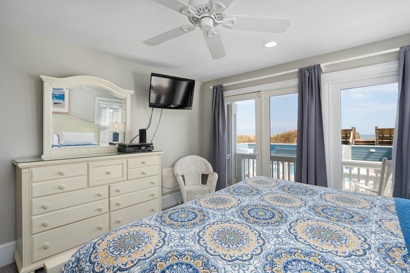Bedroom with dresser, TV, balcony.