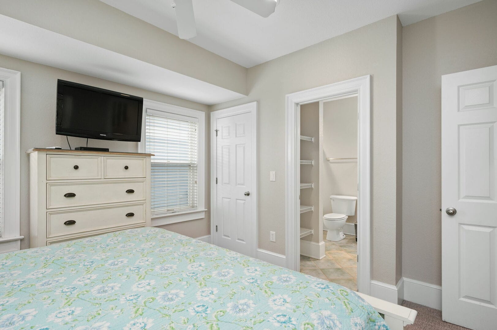 Bedroom with TV, dresser, bathroom.