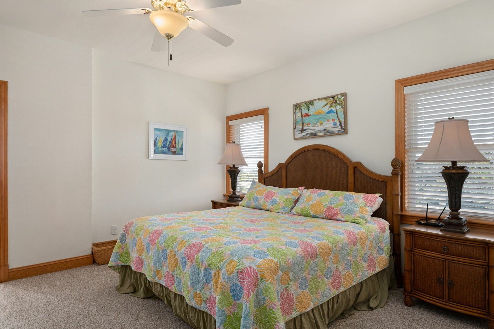 Bedroom with colorful bedspread, lamps.