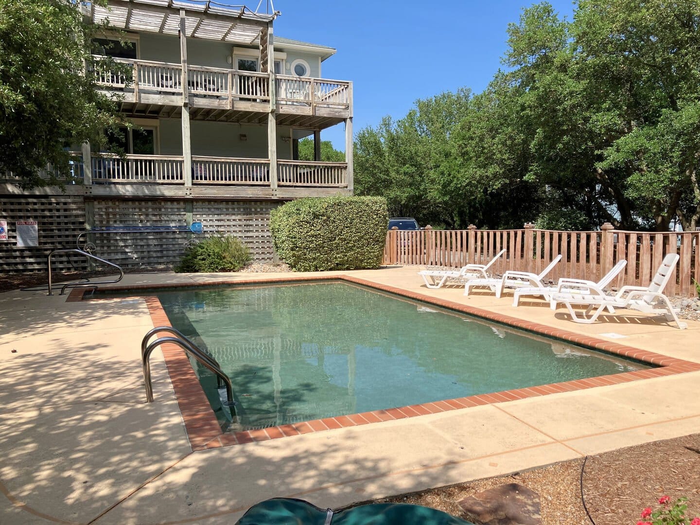 Sunny pool with loungers, building.