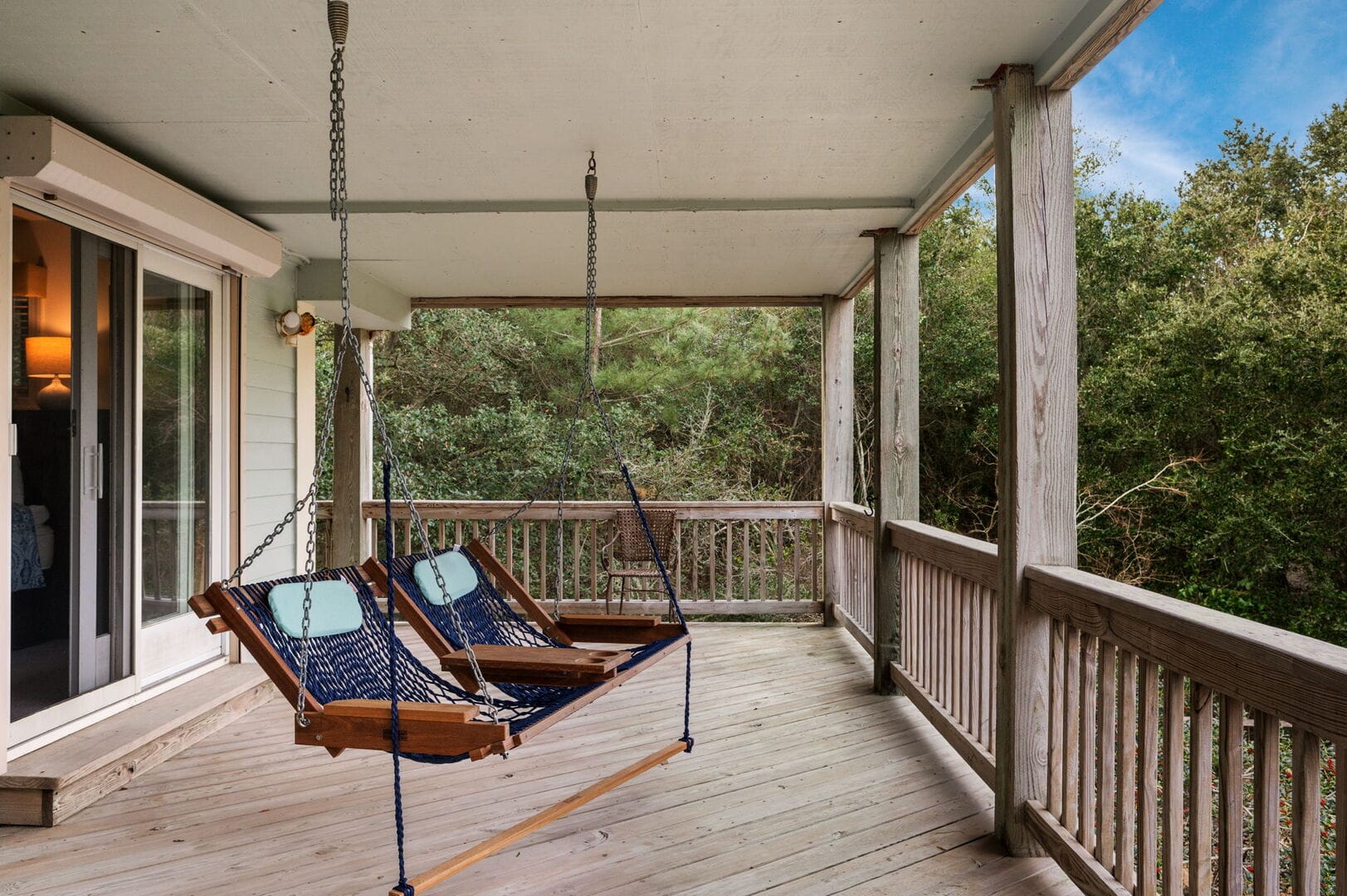 Covered porch with two hanging chairs.