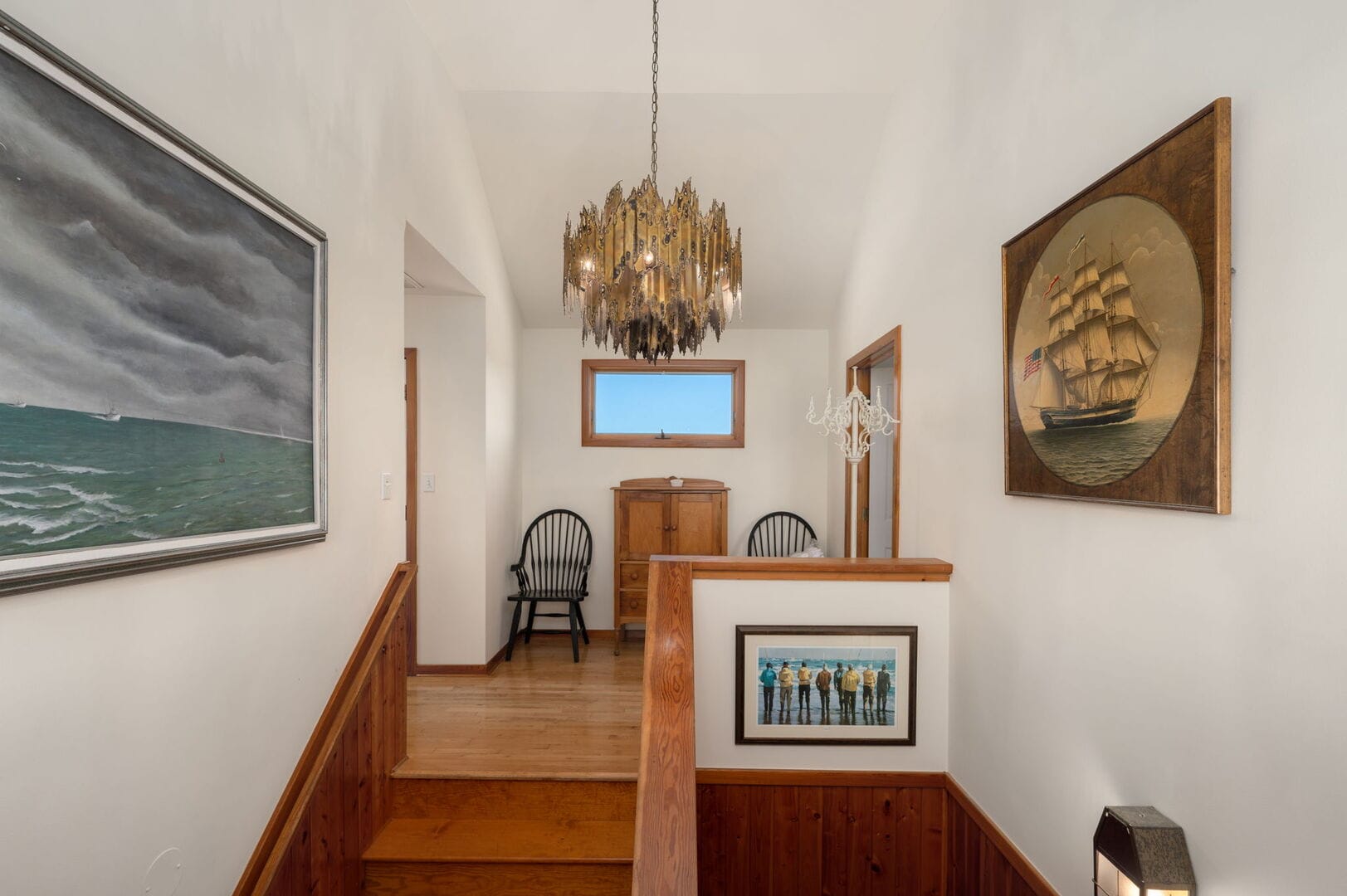 Hallway with paintings and chandelier.