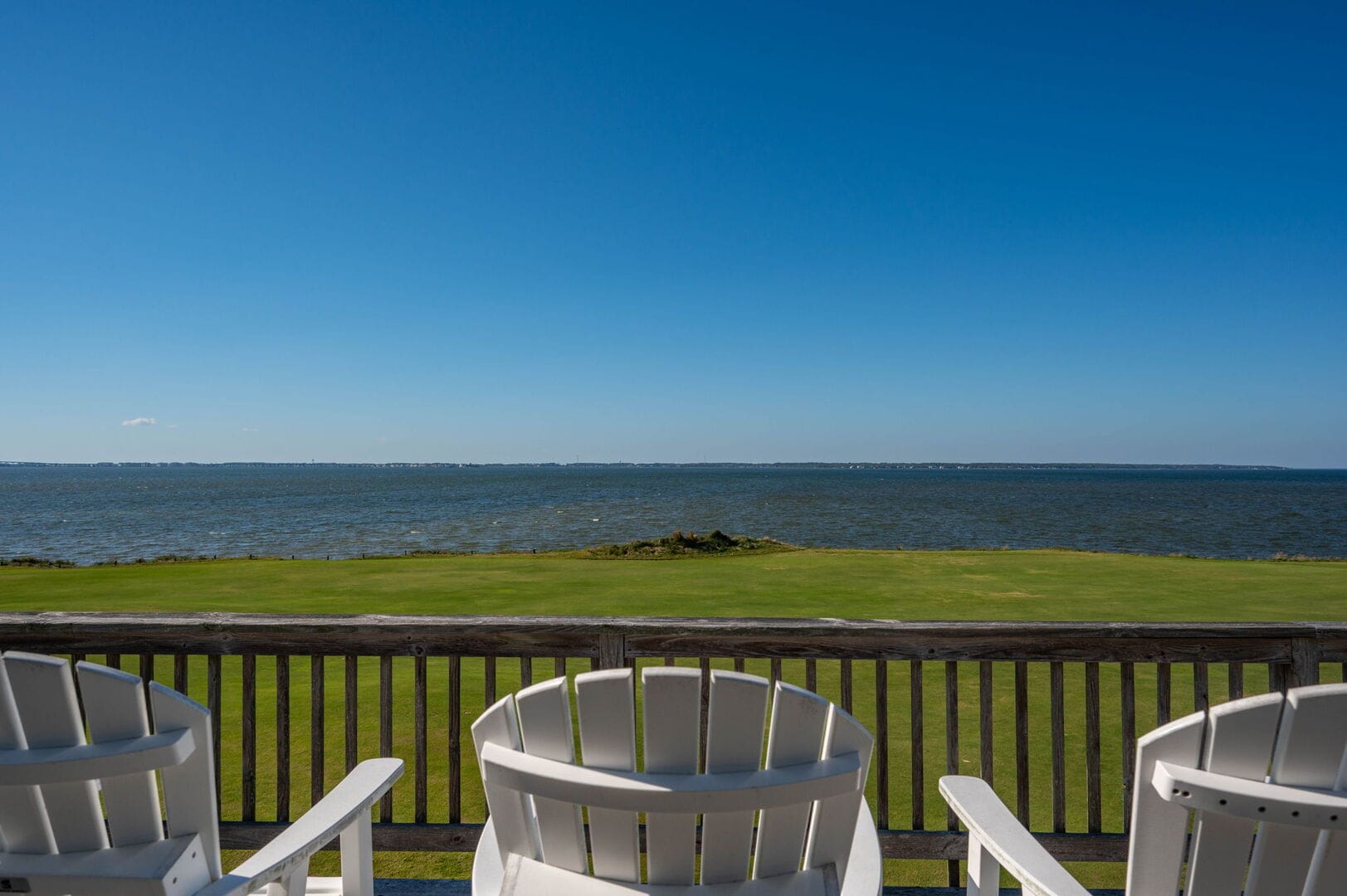 Chairs on balcony overlooking water.