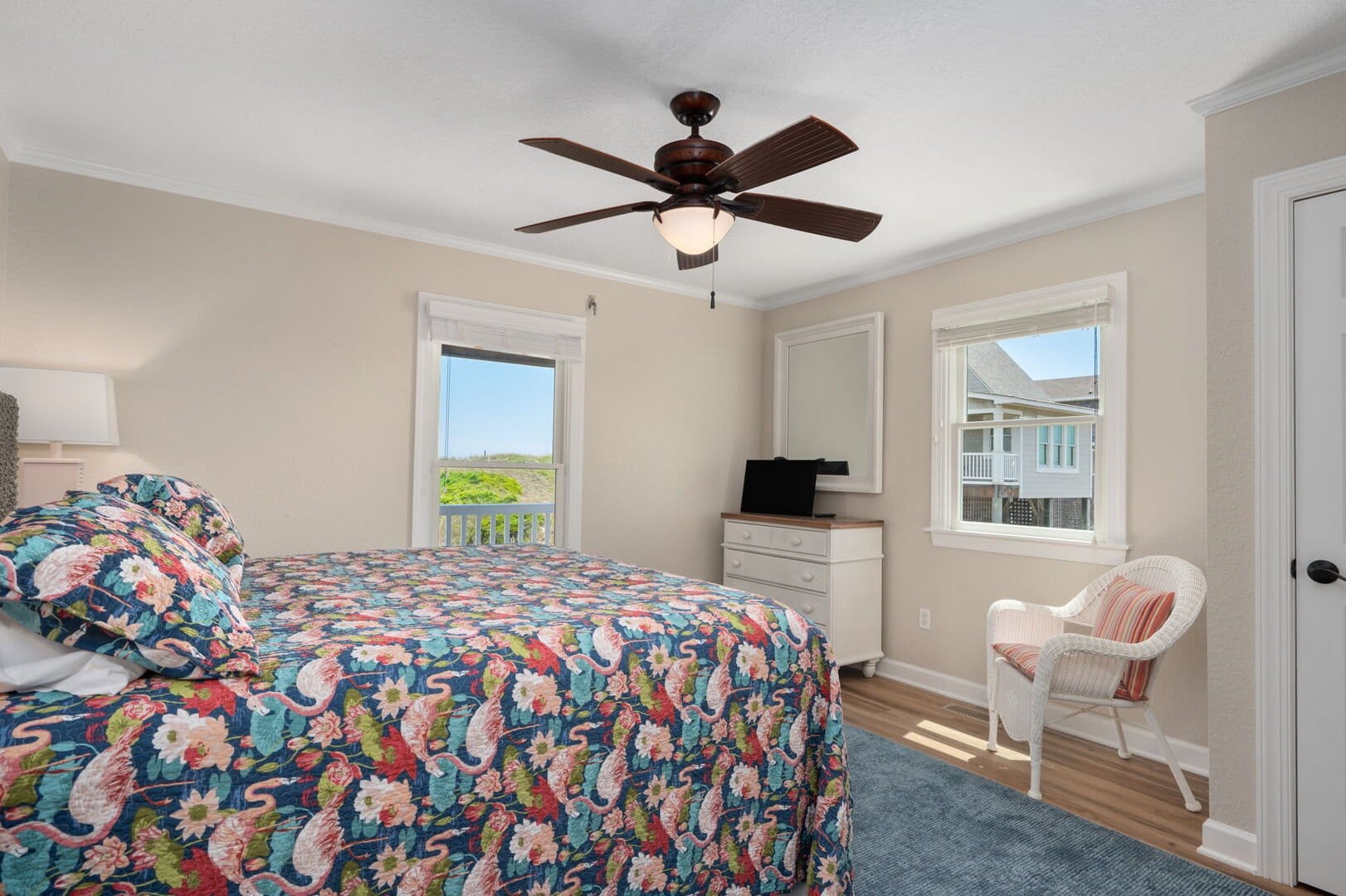 Bedroom with colorful bedspread, windows.
