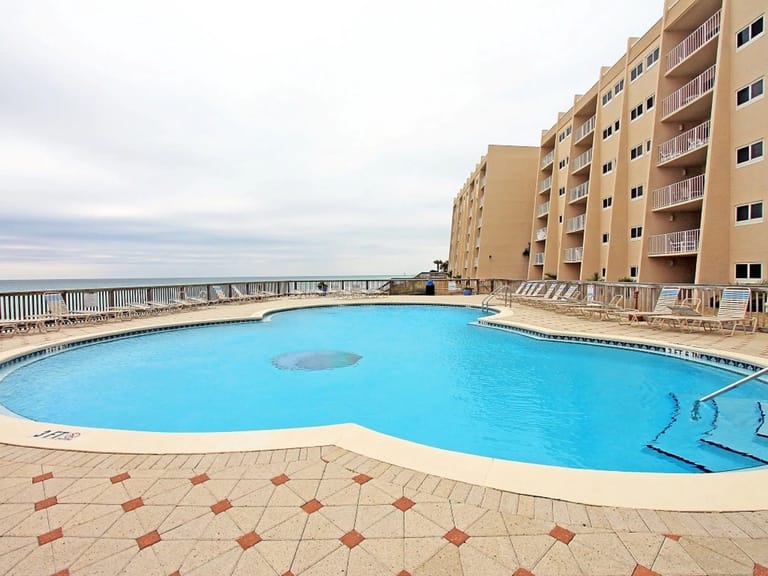 Outdoor pool beside beachfront building.