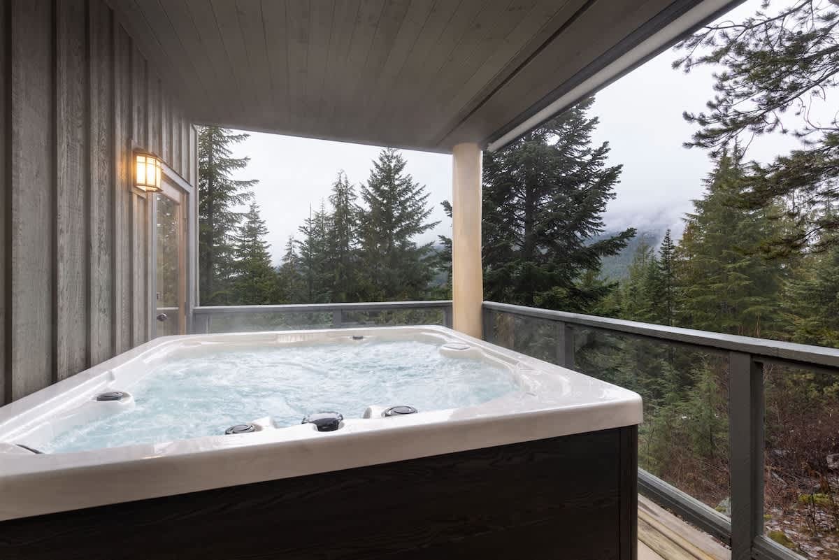 Hot tub on balcony, forest view.