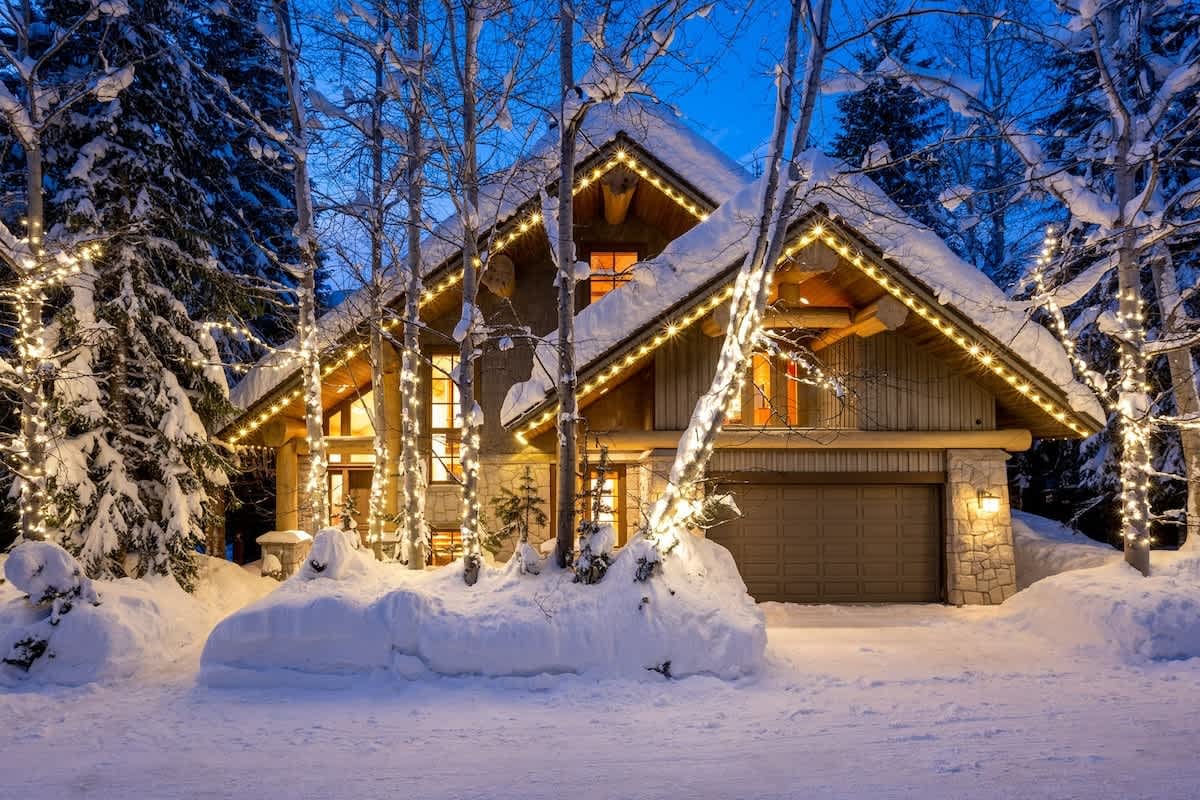 Cozy cabin with snow and lights.