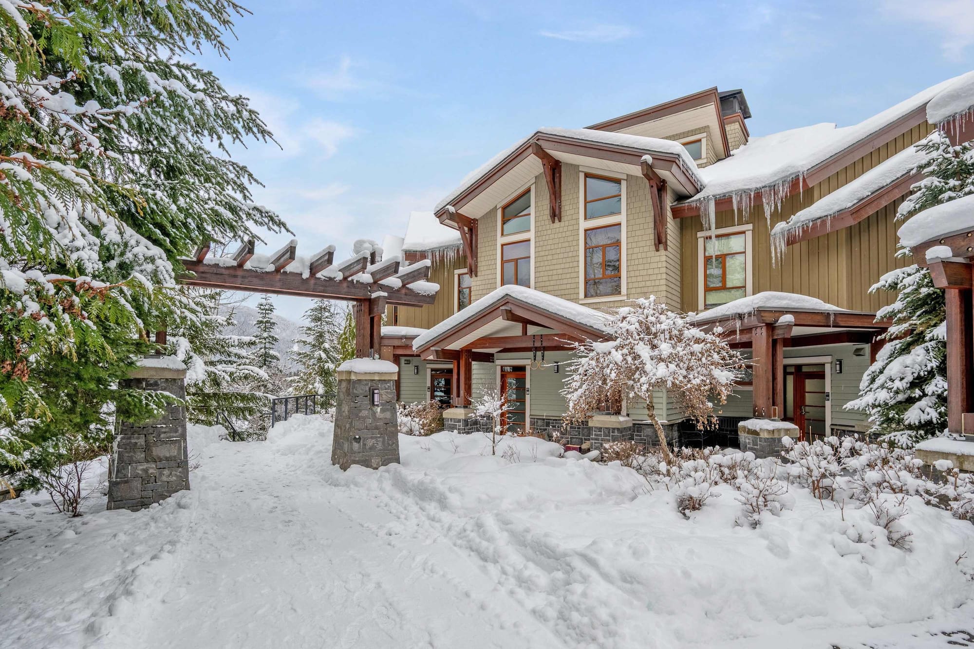 Snow-covered house with wooden archway.